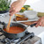Nordic Ware Verde ceramic nonstick 8-inch skillet with green exterior cooking red tomato soup on stovetop