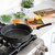 Nordic Ware Verde ceramic nonstick 10-inch skillet on stovetop with diced vegetables and herbs nearby