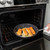 Nordic Ware Basalt 12-inch skillet with salmon fillet being placed in oven, dark non-stick surface