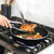 Nordic Ware Basalt black non-stick 12-inch skillet on stovetop with golden-brown seared pork chops