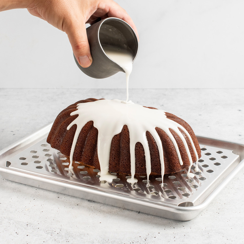 Quarter Sheet & Multi Task Rack with loaf cake, hand drizzling frosting over cake