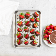 Overhead image of Quarter Sheet & Multi Task Rack with chocolate dipped strawberries, plate of strawberries and dish of chocolate next to pan
