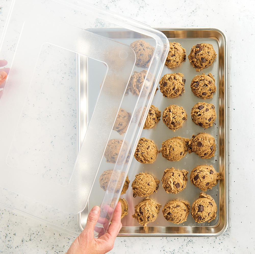 Half Sheet with cookie dough balls and hands placing a lid on top
