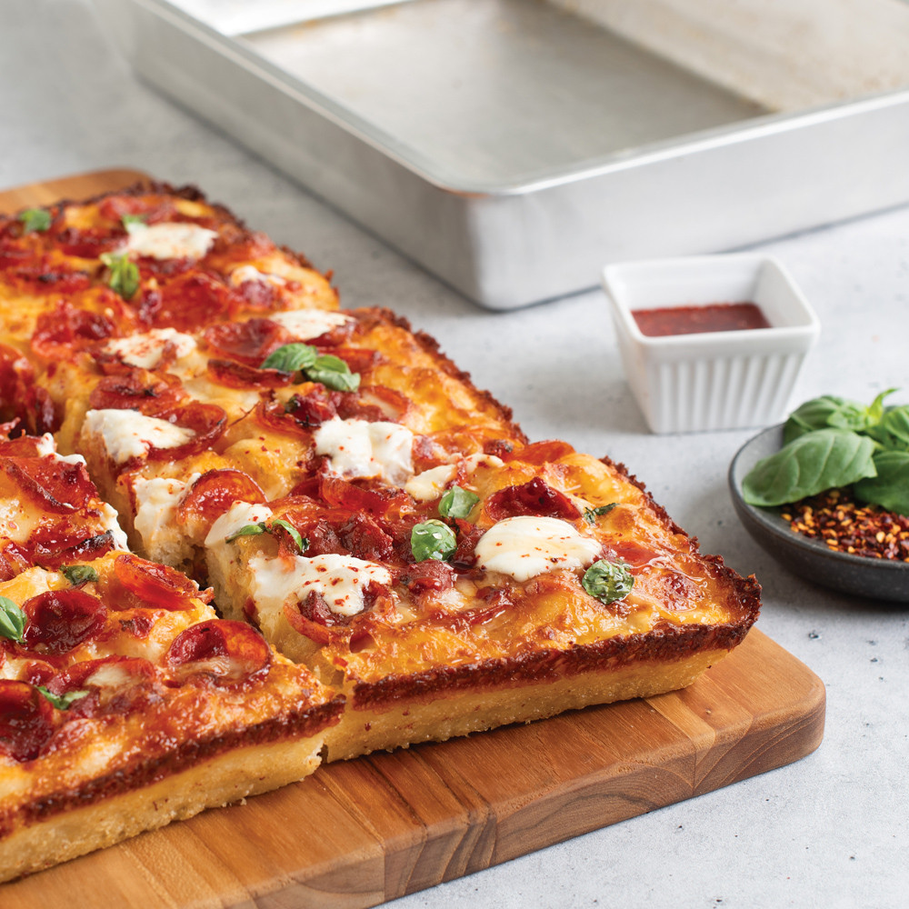 Closeup of pizza on cutting board with pan in background