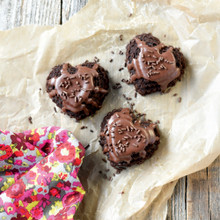 Chocolate Heart Cakelets with chocolate frosting and sprinkles on parchment paper