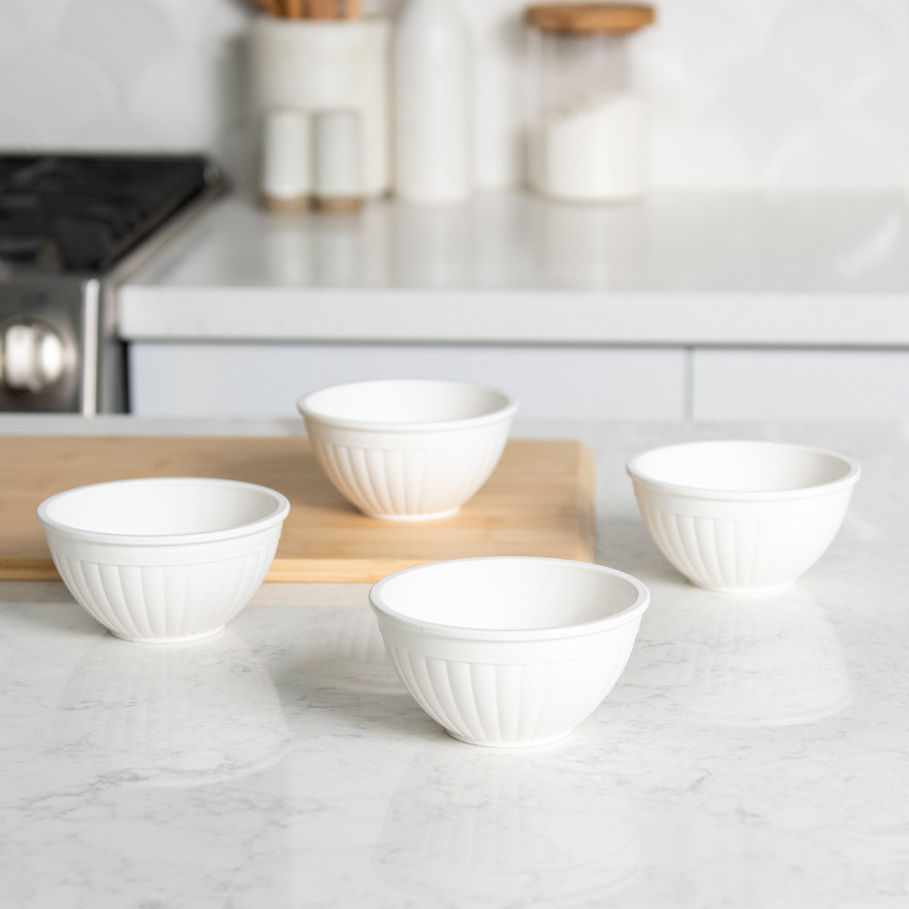 Four white mini bowls arranged separately on white countertop