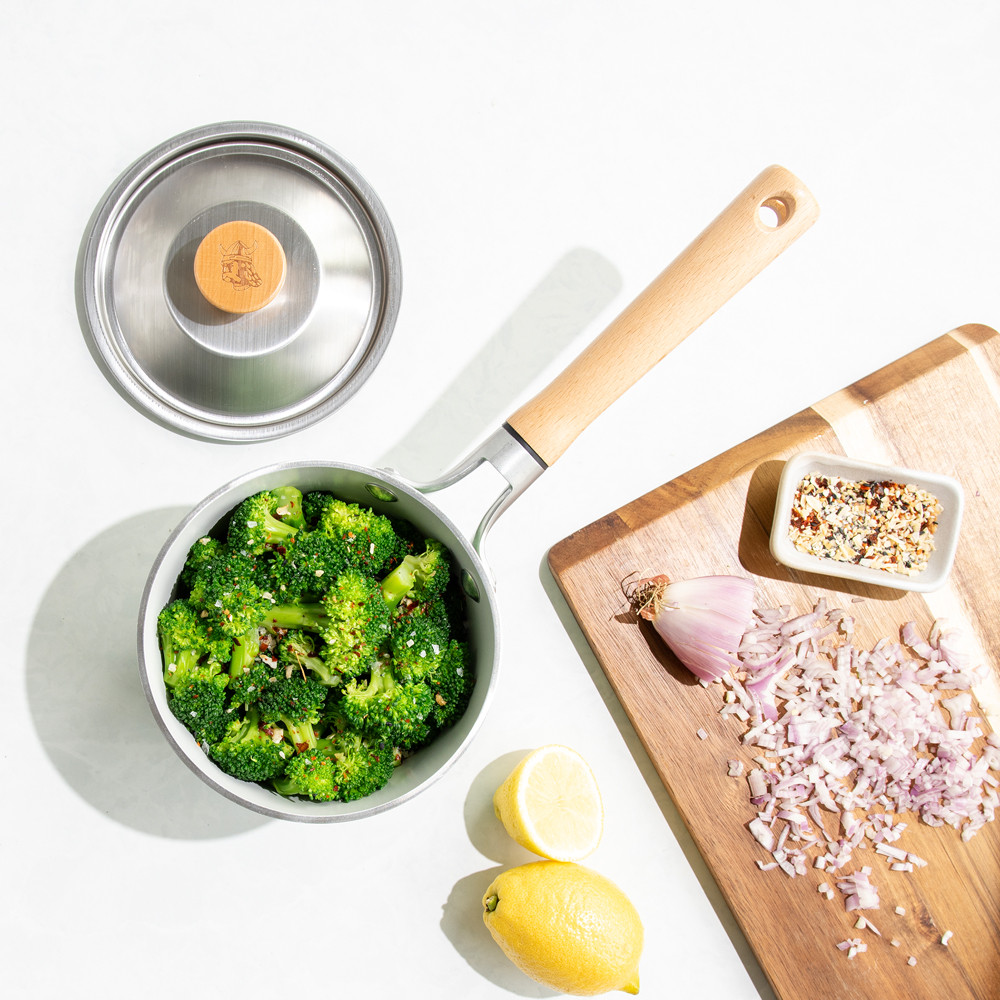 cardamom 1.5qt saucepan on with broccoli, lid next to it with cutting board of ingredients
