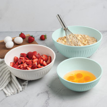 Nordic Ware 3 piece seaglass and white 5 quart, 3.5 quart and 2 quart bowls filled with dough, egg yolks, and strawberries