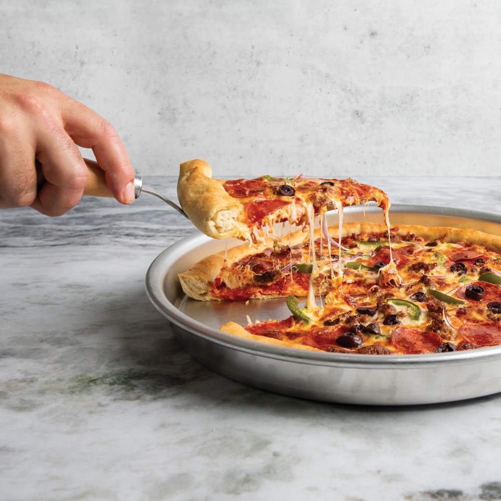 hand holding server pulling a slice of pizza from deep dish pizza pan