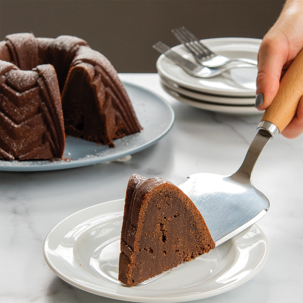 Nordic Ware stainless steel cake server lifting slice of chocolate bundt cake from decorated plate