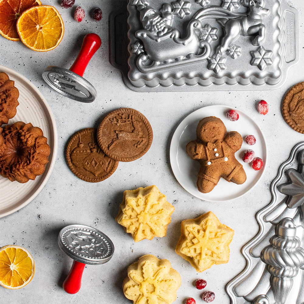 group shot of gingerbread kid cakelet, xmas cookie stamps, snowflake cakelets, santa sleigh loaf pan, and ornament cake pan