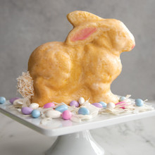 Golden glazed bunny-shaped cake baked in Nordic Ware 3D bunny cake pan, standing upright on white cake stand