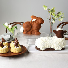Easter display featuring Nordic Ware 3D bunny cake on stand, lamb cake, and shortcake baskets with chocolate decorations