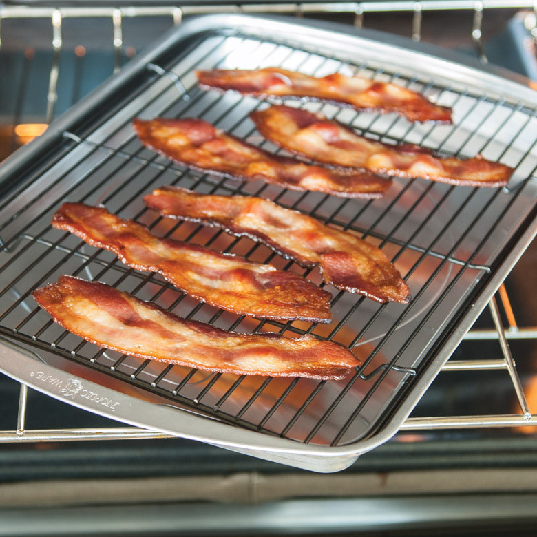 Nordic Ware aluminum oven crisp baking tray with golden-brown cooked bacon strips arranged in rows