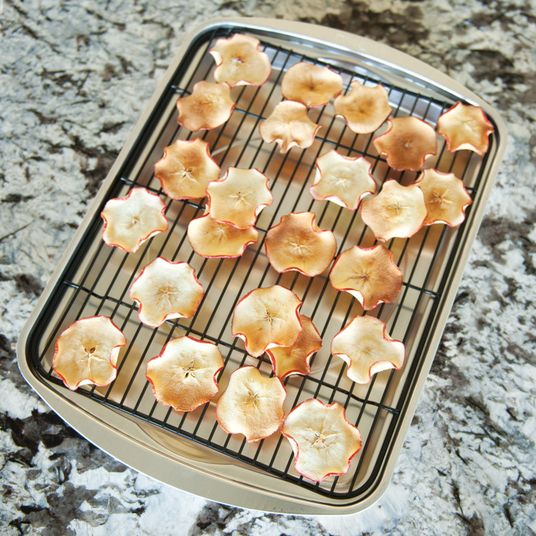 Dried apple slices arranged on Nordic Ware aluminum oven crisp baking tray with perforated surface