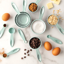 Nordic Ware sea glass colored measuring cups and spoons arranged with baking ingredients overhead view