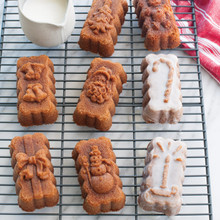 Six golden-brown mini loaves on wire cooling rack, some with white glaze drizzled on top
