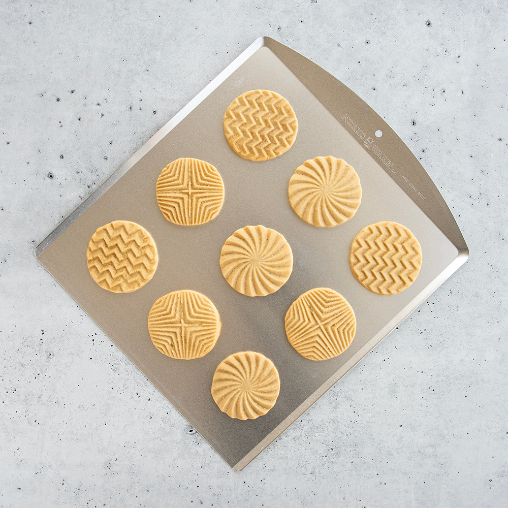 Nordic Ware aluminum cookie sheet with natural silver finish, topped with golden baked vanilla cookies
