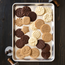 Golden baked cookies with decorative stamped patterns arranged on Nordic Ware aluminum half sheet pan