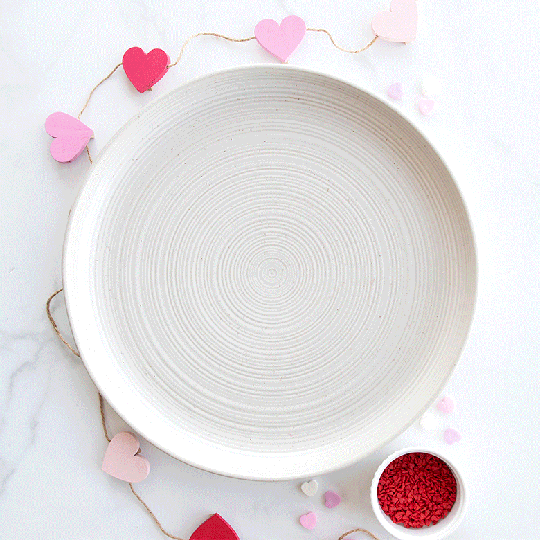 Valentine's Day charcuterie board with heart-shaped cookies, chocolate treats, and berries arranged on wooden surface