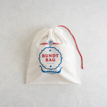 Navy blue drawstring storage bag containing aluminum bundt pan, bag opening shows fluted pan interior