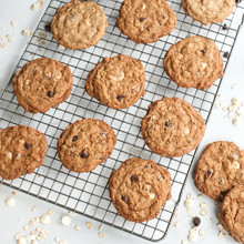Golden baked chocolate chip cookies cooling on Nordic Ware nonstick grid rack over aluminum half sheet pan