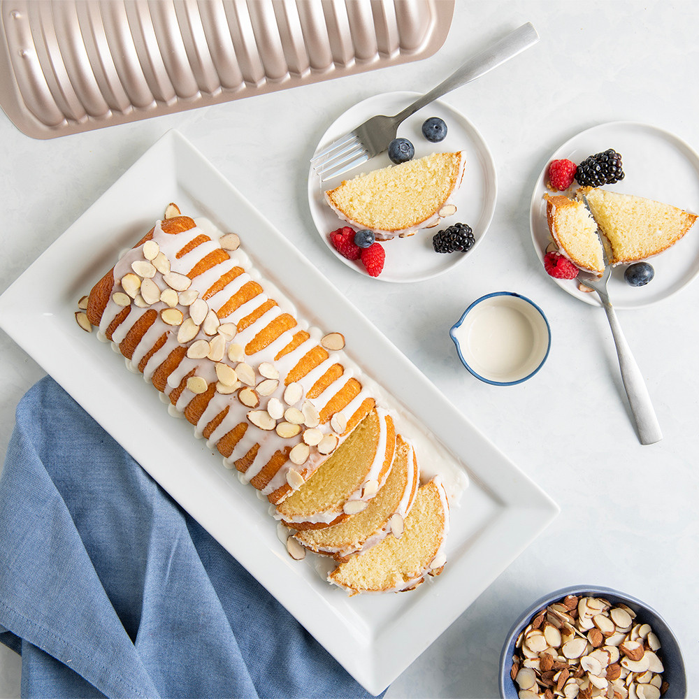 Golden glazed almond cake in Nordic Ware's detailed aluminum loaf pan, topped with sliced almonds