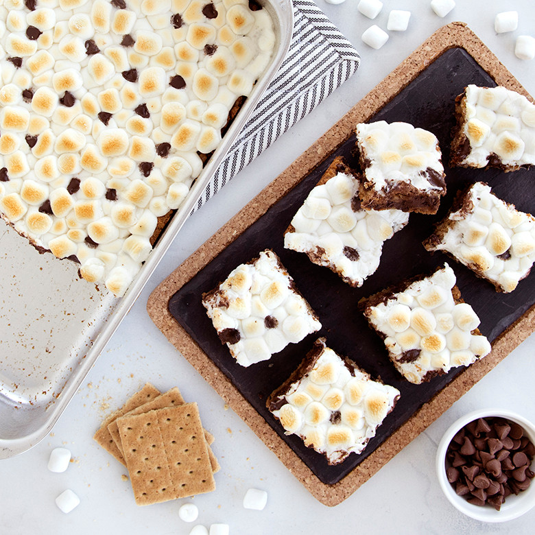 Golden s'mores bars cut into squares on white platter, baked in Nordic Ware aluminum rectangular baking pan