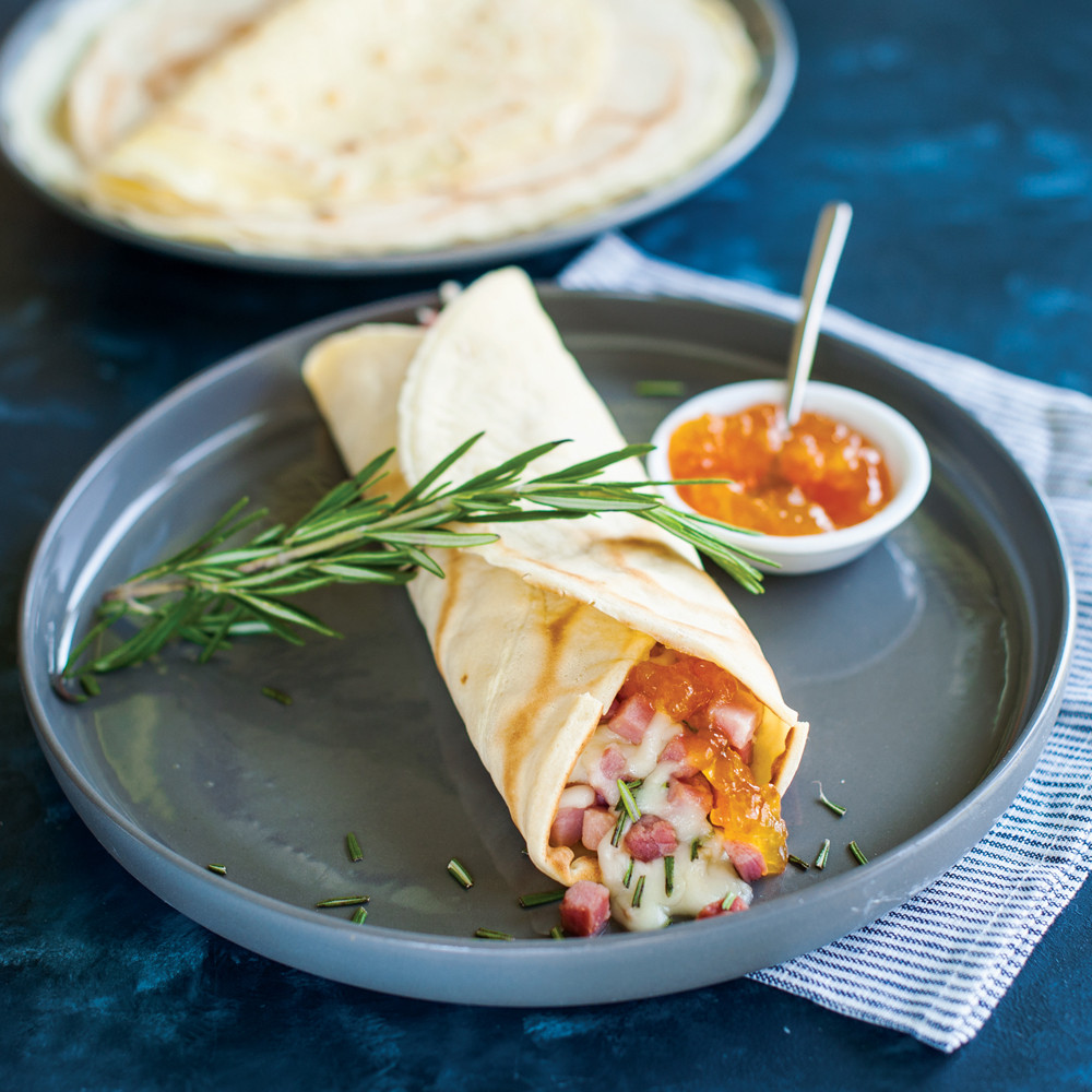 Savory crepe filled with ham and cheese on white plate, made using Nordic Ware French steel crepe pan