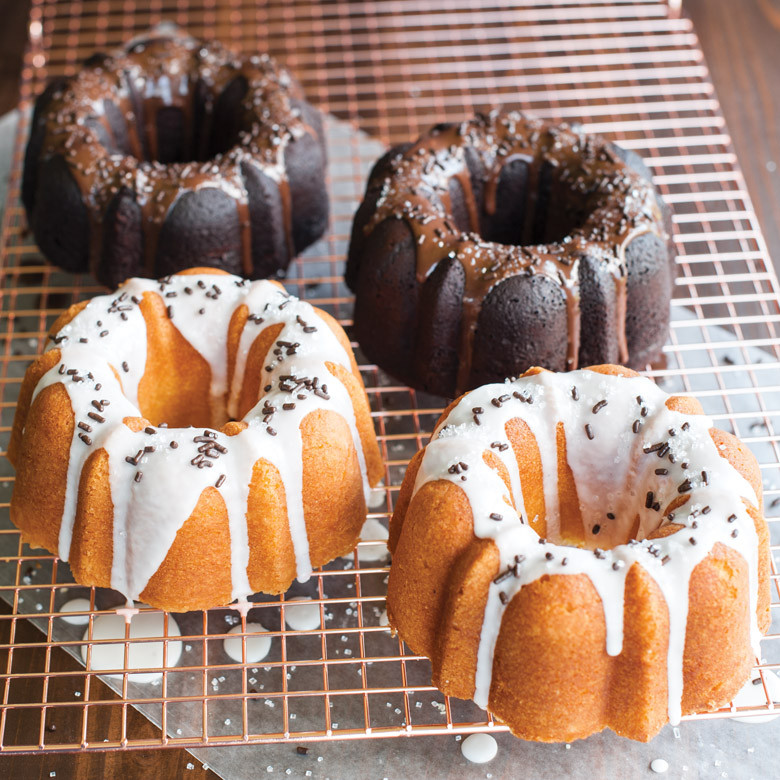 Two mini bundt cakes from Nordic Ware 3-cup bundt pan, one chocolate with white glaze, one vanilla with brown glaze