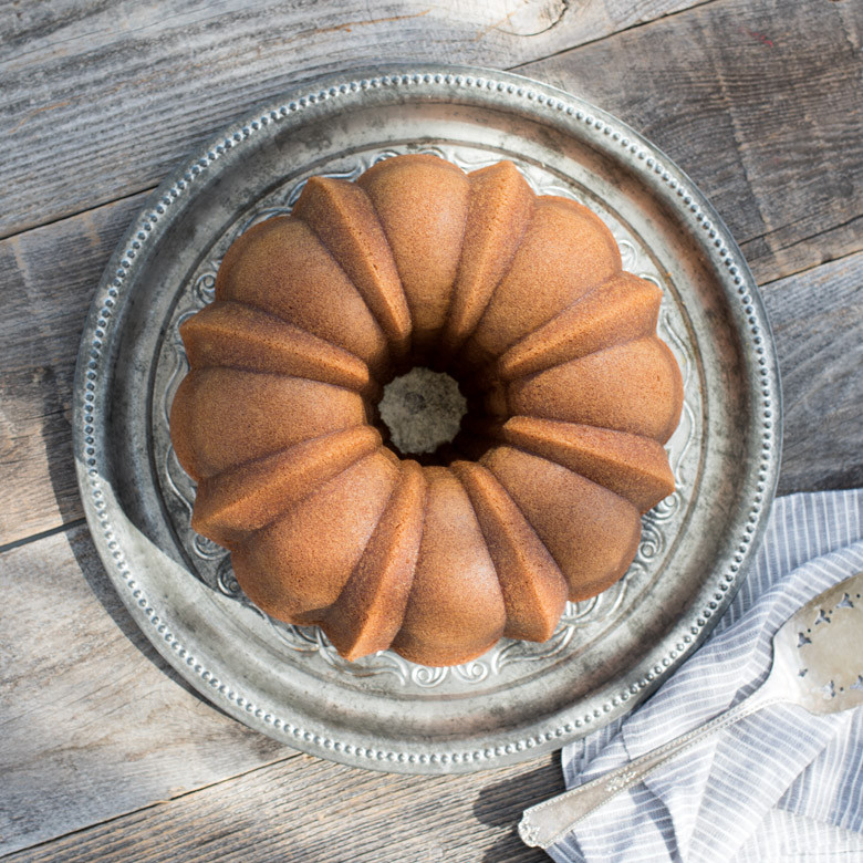 Plain golden bundt cake baked in Nordic Ware Silver Anniversary bundt pan, showing intricate fluted design