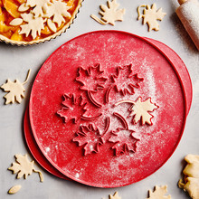 Nordic Ware aluminum pie top cutter with leaf-shaped cutouts, dusted with flour alongside cut pastry leaves