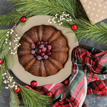 Golden bundt cake baked in fluted Nordic Ware Anniversary pan with holiday greenery and wrapped gift