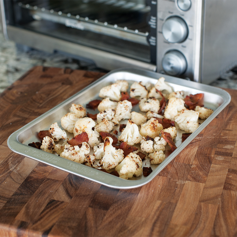 Golden roasted cauliflower florets on Nordic Ware aluminum compact baking sheet, natural silver finish