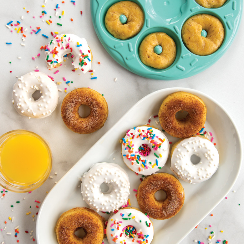 Nordic Ware aluminum donut bites pan with 12 mini glazed donuts, topped with colorful sprinkles and cinnamon sugar