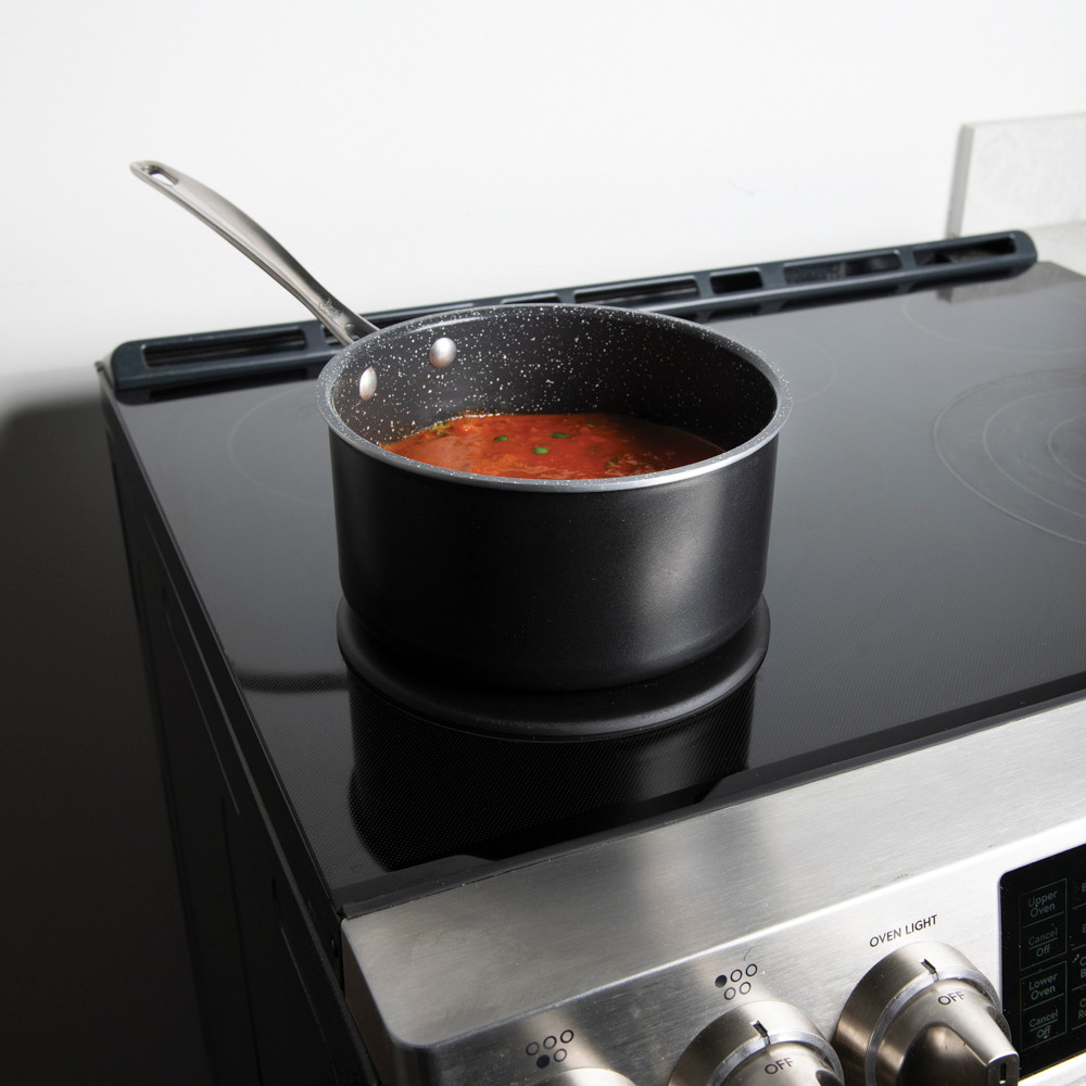 Lifestyle image of saucepan on heat tamer over an induction stove