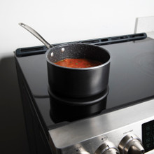 Lifestyle image of saucepan on heat tamer over an induction stove