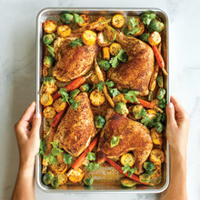 Nordic Ware aluminum half sheet pan with golden roasted chicken thighs and colorful vegetables, caramelized