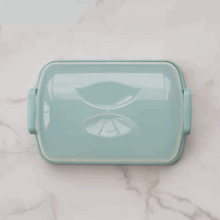 Nordic Ware clear plastic cake carrier with domed lid and white base, showing assembly process