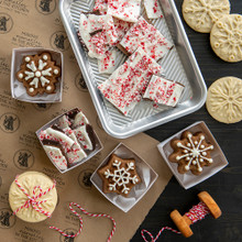 Nordic Ware snowflake cakelet pan with baked golden treats, gift boxes and winter decorations