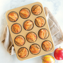 Nordic Ware aluminum muffin pan with 12 cavities filled with golden-brown baked apple muffins