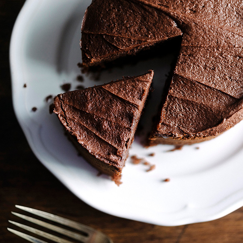Chocolate layer cake with one slice cut, baked in Nordic Ware 9-inch round cake pan on white platter