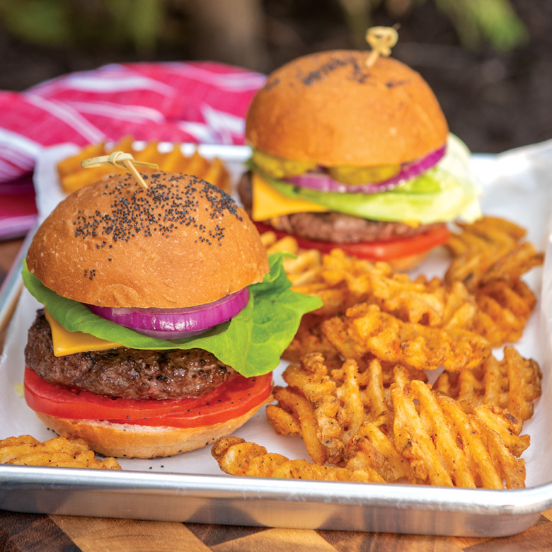 Nordic Ware aluminum grill tray with two cooked hamburgers and golden french fries, rectangular serving platter