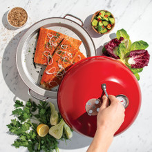 Hand removing lid of Indoor/Outdoor Kettle Smoker with smoked salmon reveal and ingredients on surface