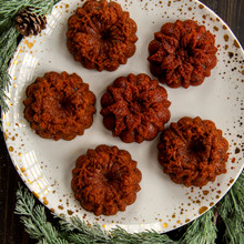 Six golden mini wreath cakes from Nordic Ware Wreathlettes pan arranged on white plate with holiday decorations