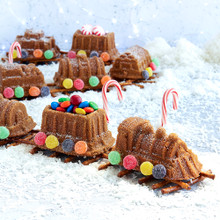 Decorated train-shaped cake with colorful candies arranged on pretzel track, baked in Nordic Ware train cake pan