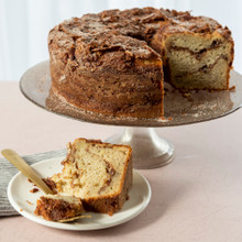 Golden tube cake with one slice cut, baked in Nordic Ware aluminum tube pan showing tall round shape