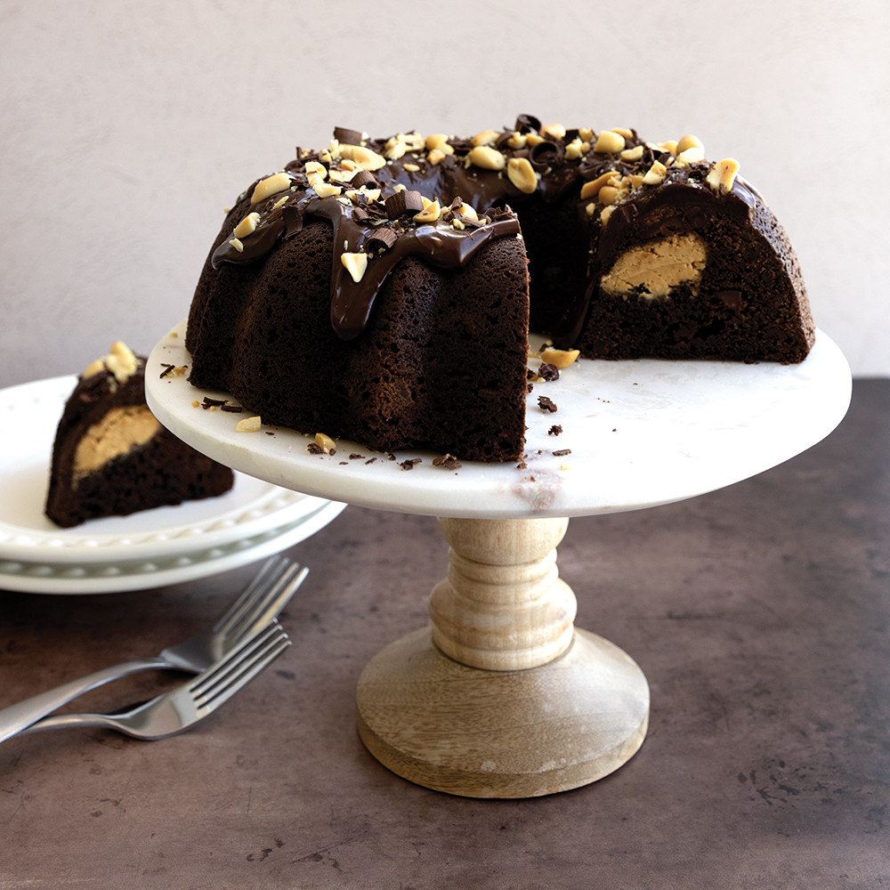 Chocolate bundt cake with chocolate glaze and chopped nuts, slice removed showing moist interior texture
