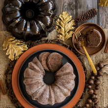 Sliced cinnamon sugar bundt cake on white platter next to Nordic Ware bronze cast aluminum bundt pan