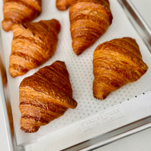 Golden baked croissants on Nordic Ware perforated aluminum half sheet pan with natural silver finish